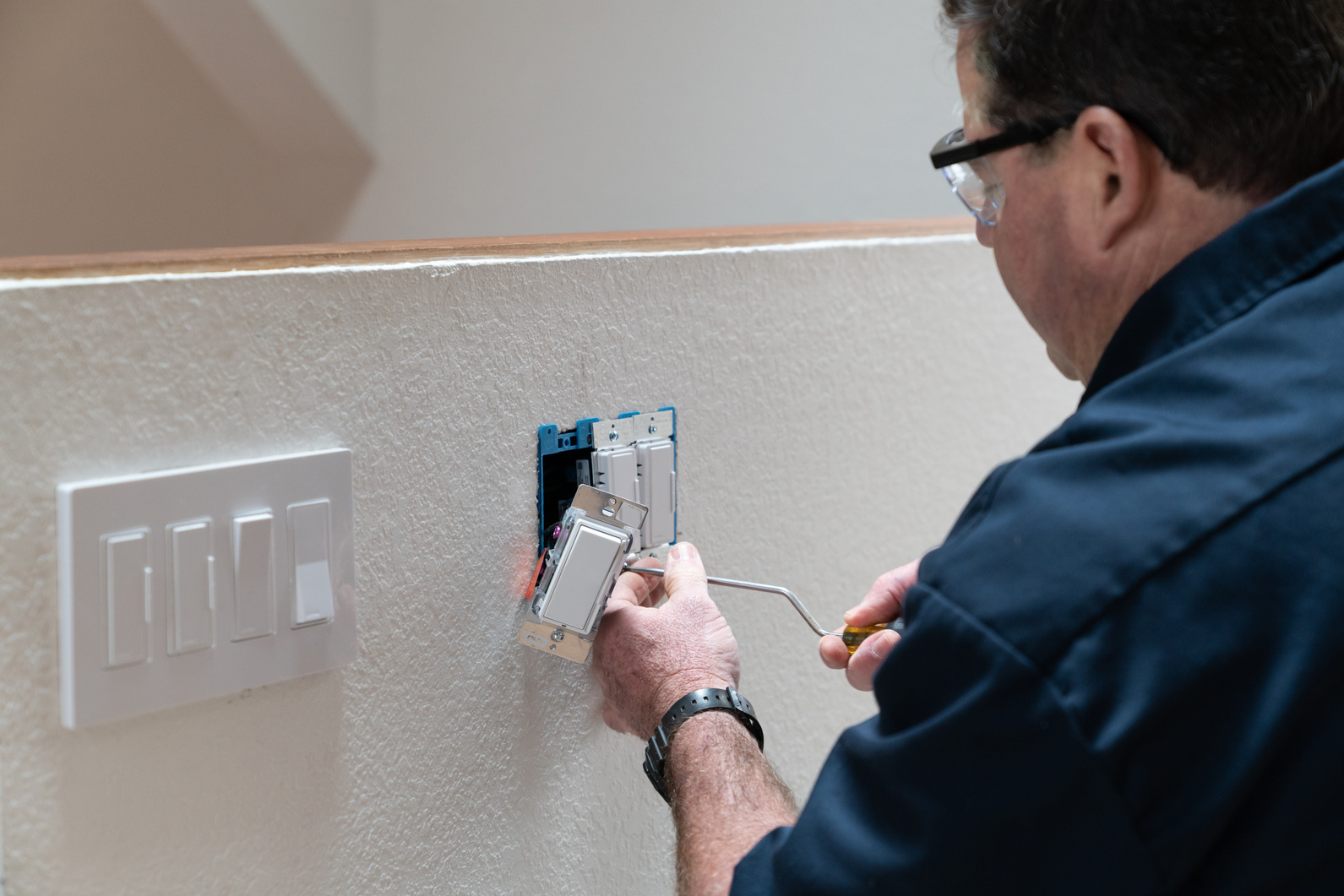 Electrician working in home installing dimmer switched in wall