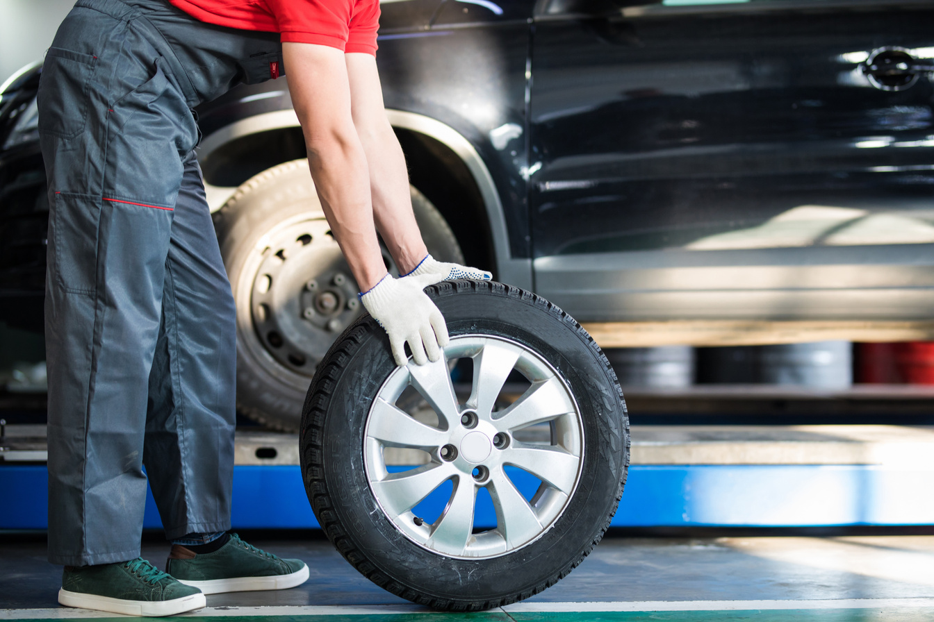 Auto mechanic carrying tire in tire store