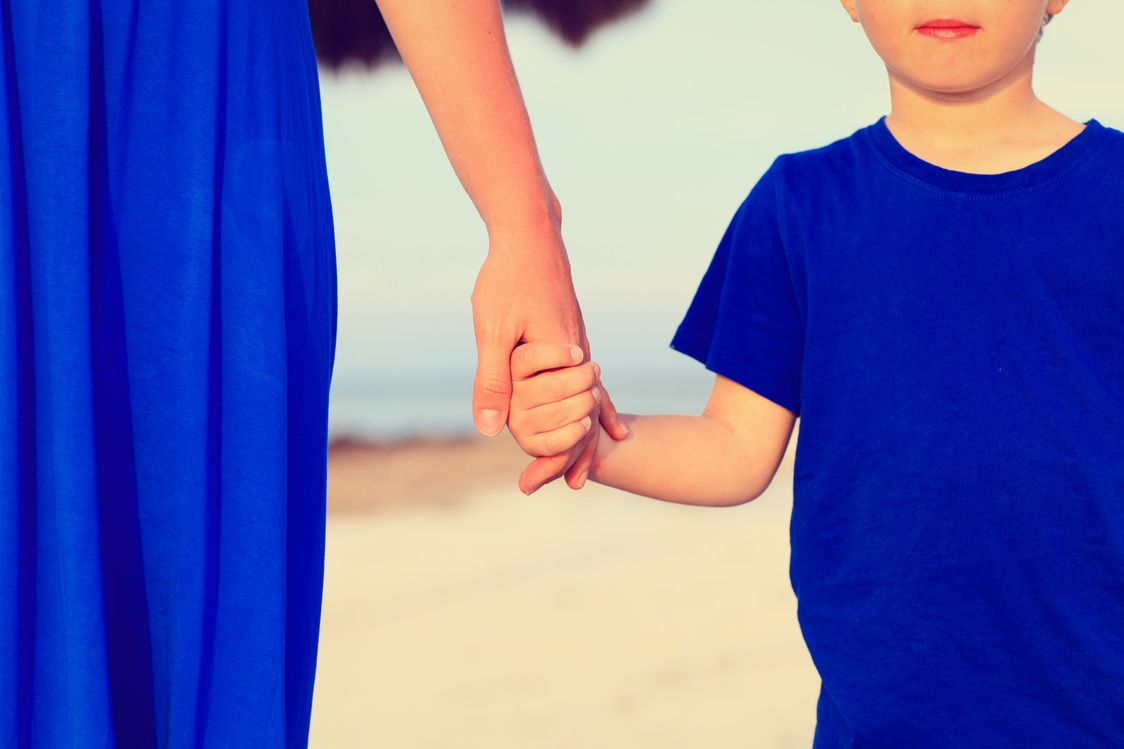 mother and son holding hands on beach